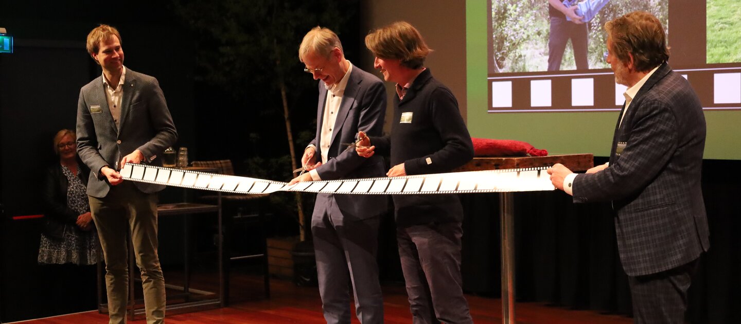 mannen knippen lint op podium tijdens filmpremiere