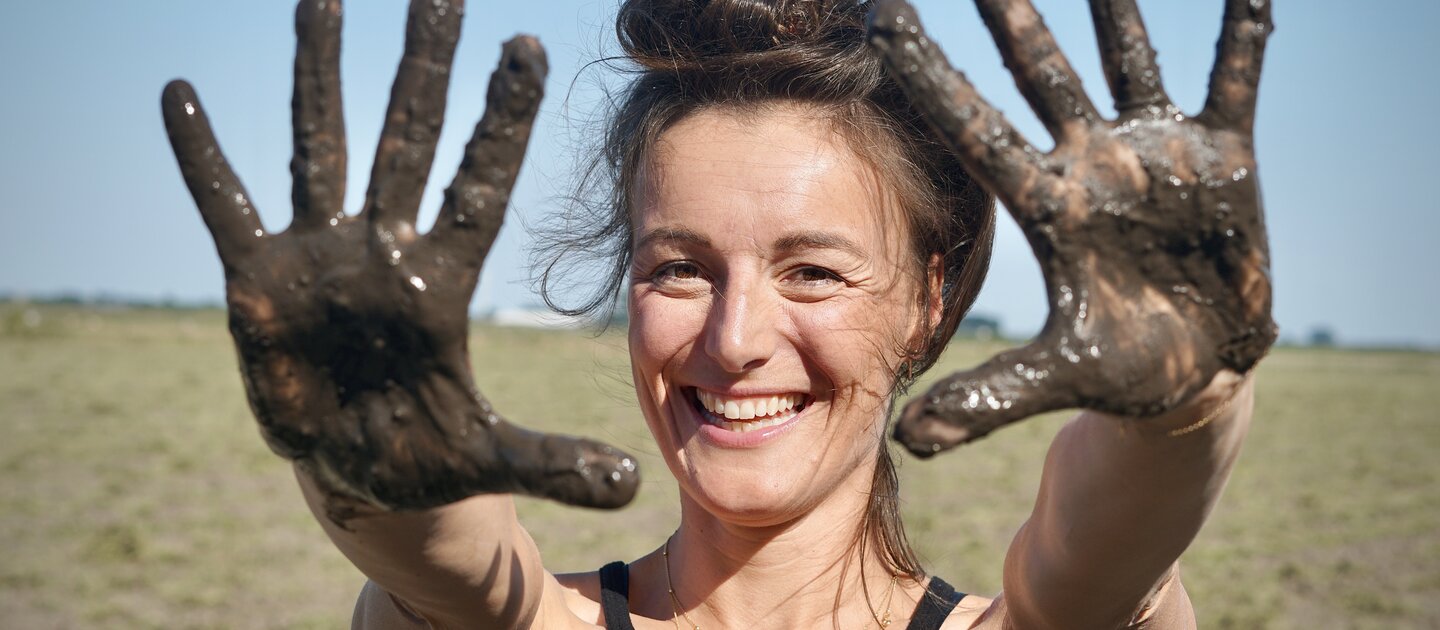 vrouw lacht modder op handen